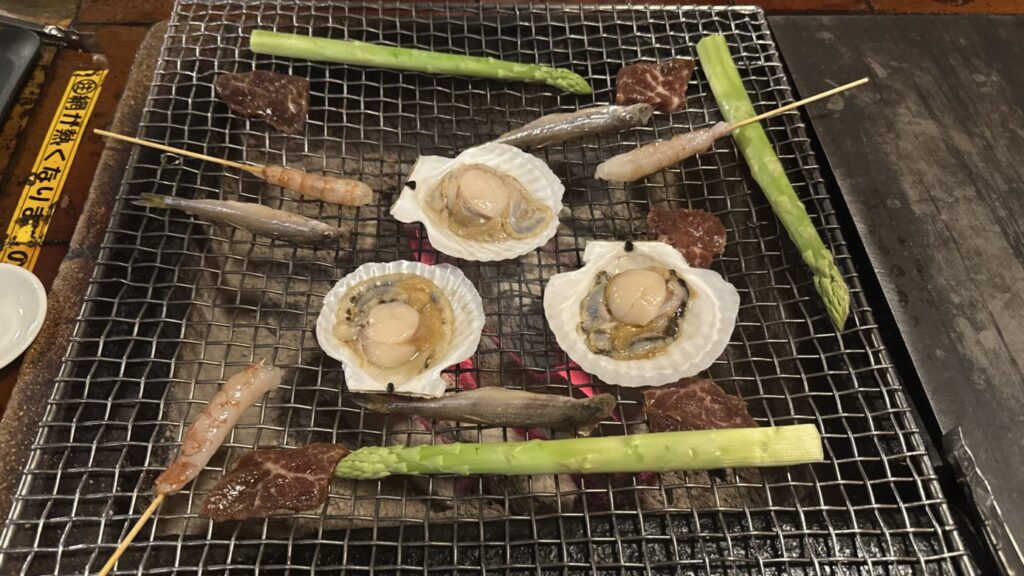 炉ばた煉瓦の炉で焼く3枚の殻付きホタテ